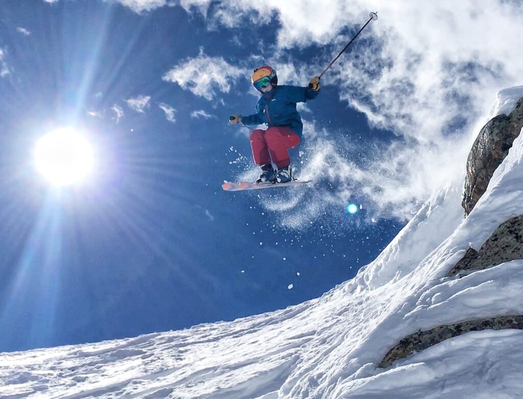 Griffin Larson in the air off a cliff, with the sun shining in the background.